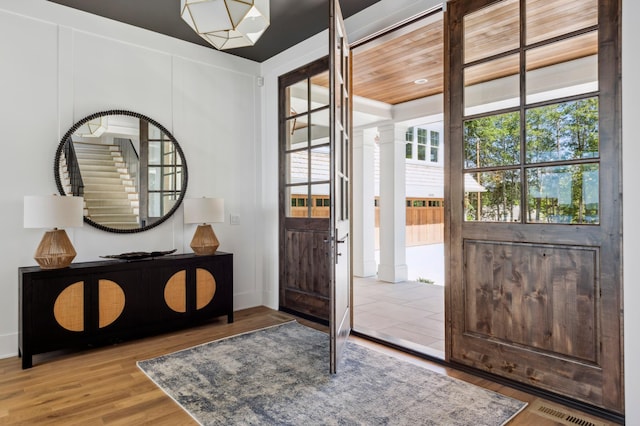 entryway with light wood-type flooring and wooden ceiling