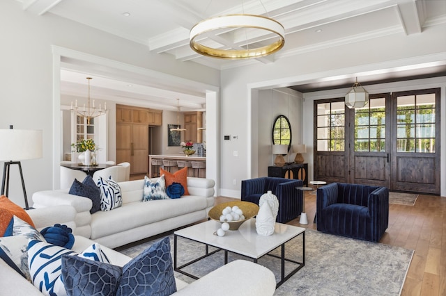 living room with a wealth of natural light, crown molding, wood-type flooring, beam ceiling, and a chandelier