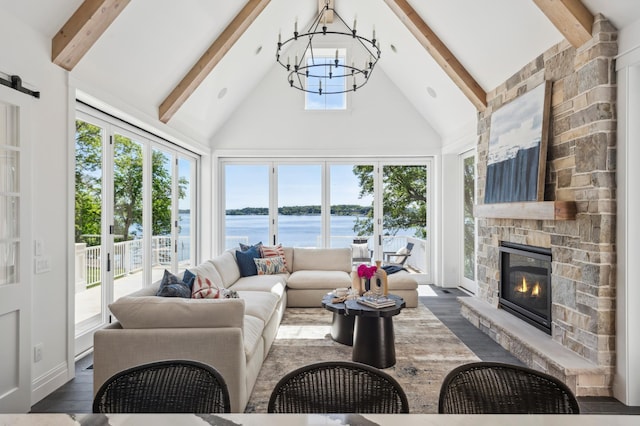 living room with a wealth of natural light, a fireplace, a water view, and a notable chandelier