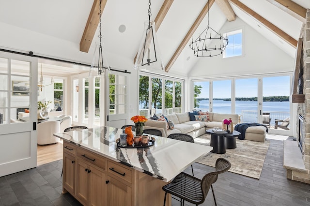 sunroom featuring lofted ceiling with beams, a barn door, a water view, and a chandelier