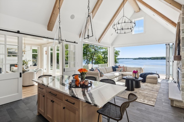 sunroom / solarium with a barn door, an inviting chandelier, a water view, and vaulted ceiling with beams