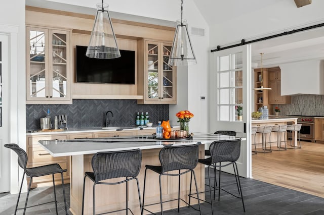 bar featuring lofted ceiling, luxury range, sink, hardwood / wood-style flooring, and a barn door