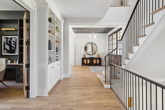 hall with built in features and light wood-type flooring