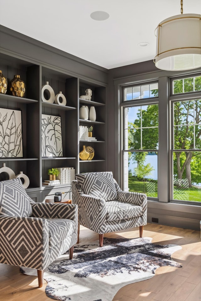 living area featuring wood-type flooring, built in features, and plenty of natural light