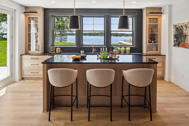 bar with decorative light fixtures, a water view, and plenty of natural light