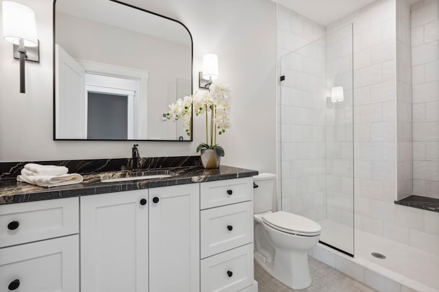 bathroom with tiled shower, vanity, tile patterned floors, and toilet