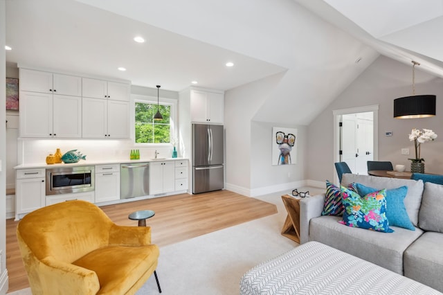 living room with sink, light hardwood / wood-style floors, and lofted ceiling