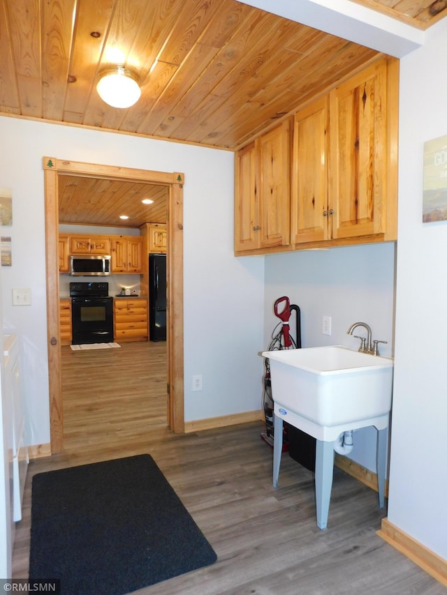 interior space with light wood-type flooring, sink, black appliances, and wood ceiling