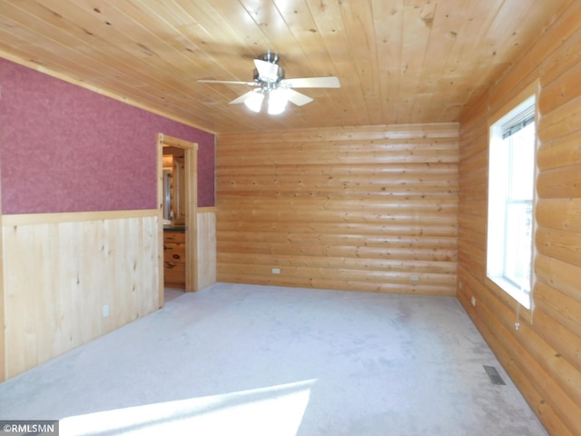 empty room with ceiling fan, wood ceiling, and log walls