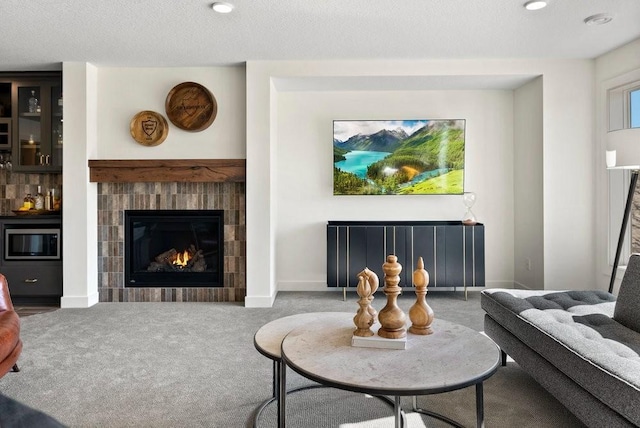 living area featuring a textured ceiling, carpet flooring, a tile fireplace, and baseboards