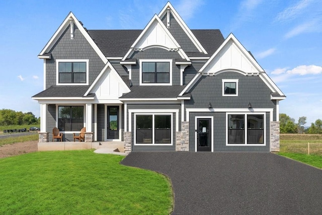 craftsman-style house with roof with shingles, a porch, and a front lawn