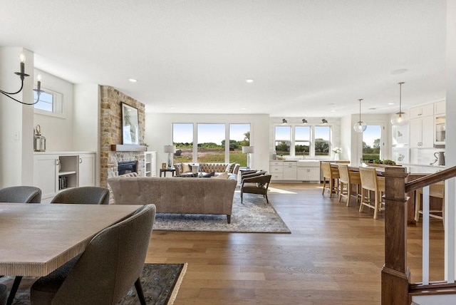 living room featuring recessed lighting, wood finished floors, and a stone fireplace