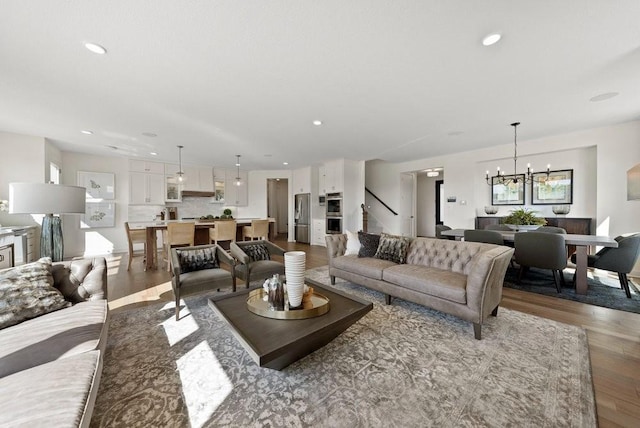 living area with stairway, recessed lighting, wood finished floors, and a notable chandelier