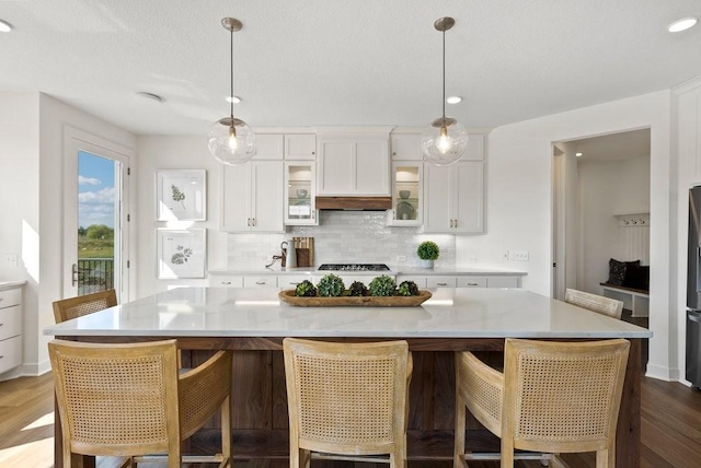 kitchen with white cabinetry, glass insert cabinets, light countertops, and a large island