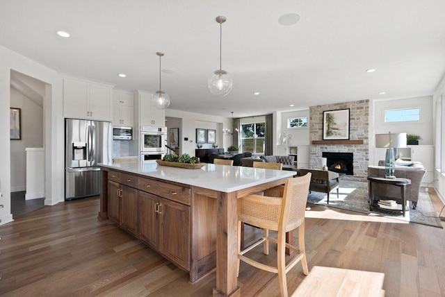 kitchen with white cabinets, open floor plan, light countertops, appliances with stainless steel finishes, and a center island