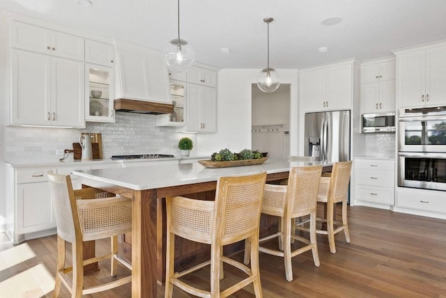 kitchen with a kitchen island with sink, white cabinetry, stainless steel appliances, and light countertops