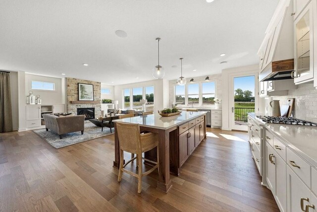 kitchen with glass insert cabinets, a kitchen island, white cabinetry, light countertops, and decorative light fixtures