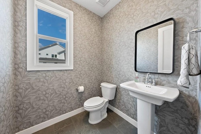 bathroom with visible vents, toilet, a sink, and baseboards