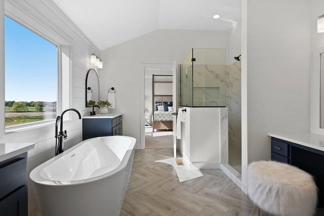 ensuite bathroom with a marble finish shower, lofted ceiling, ensuite bathroom, vanity, and a freestanding tub