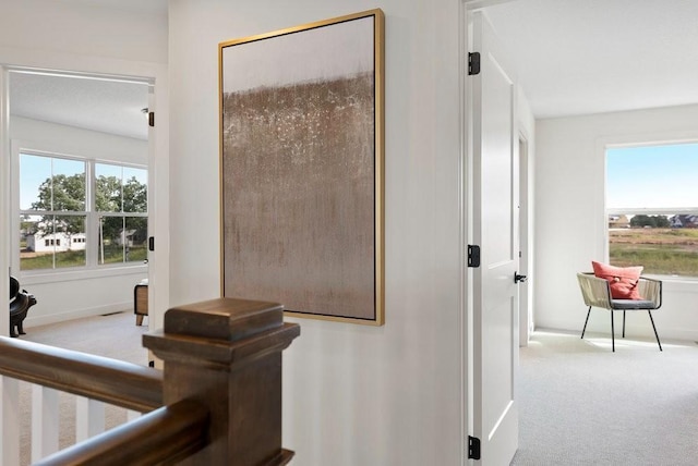 hallway featuring light carpet and baseboards