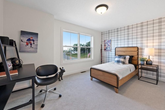 bedroom featuring baseboards, a textured ceiling, visible vents, and light colored carpet