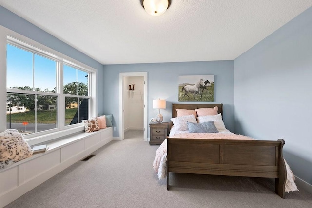 bedroom featuring light carpet, baseboards, visible vents, and a textured ceiling