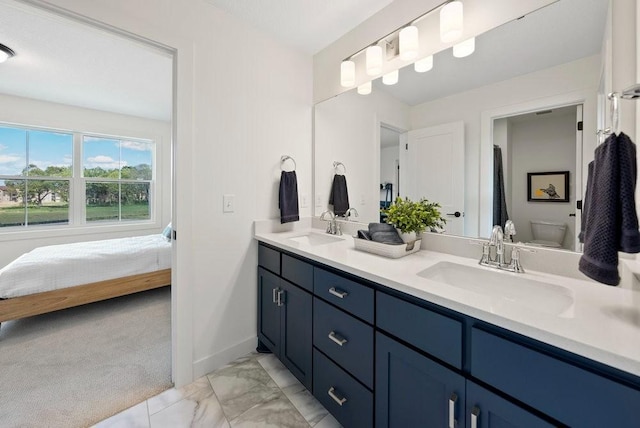 ensuite bathroom with toilet, marble finish floor, a sink, and ensuite bathroom