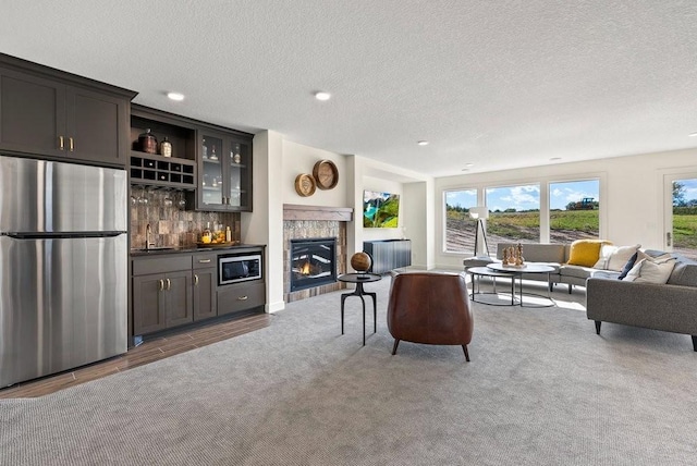 living room featuring a glass covered fireplace, a textured ceiling, a bar, and recessed lighting