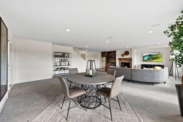 dining room with recessed lighting, a warm lit fireplace, light carpet, and baseboards