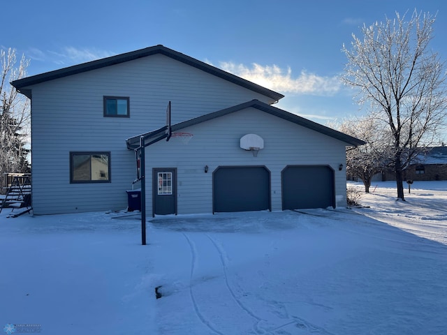 snow covered property with a garage