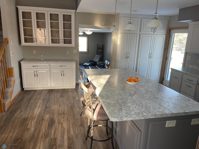 kitchen featuring a breakfast bar, a center island, dark wood-type flooring, and decorative light fixtures