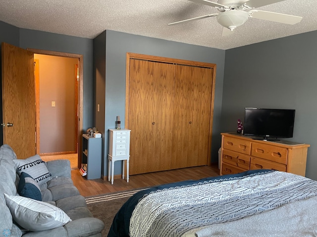 bedroom with ceiling fan, a closet, dark wood-type flooring, and a textured ceiling