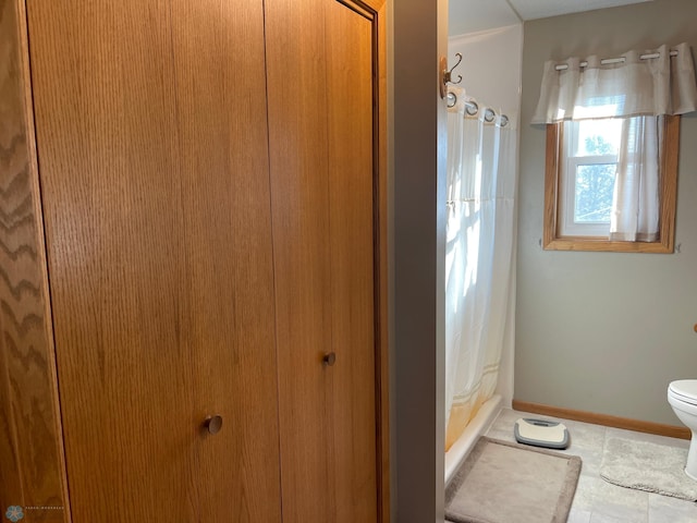 bathroom featuring tile patterned floors, toilet, and walk in shower