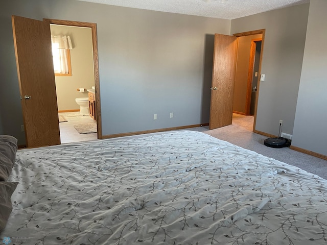 carpeted bedroom featuring a textured ceiling and ensuite bath