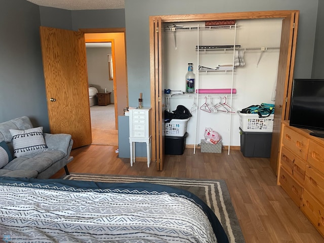 bedroom with a textured ceiling, dark hardwood / wood-style floors, and a closet