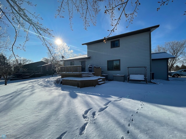 snow covered rear of property with a wooden deck