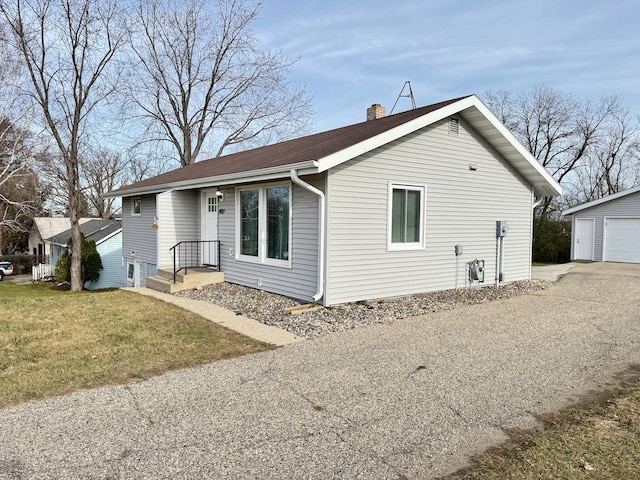 view of side of property featuring a garage, a yard, and an outbuilding