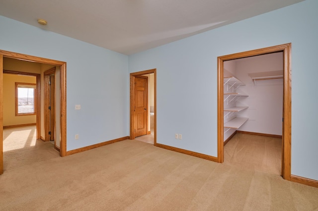 unfurnished bedroom with a spacious closet, a closet, and light carpet