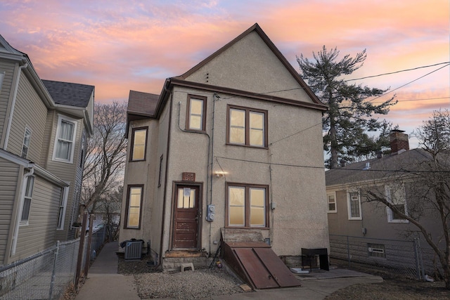 view of front of house with central AC, fence, and stucco siding