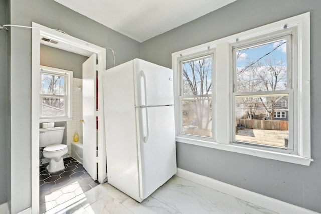 kitchen with freestanding refrigerator, marble finish floor, visible vents, and baseboards