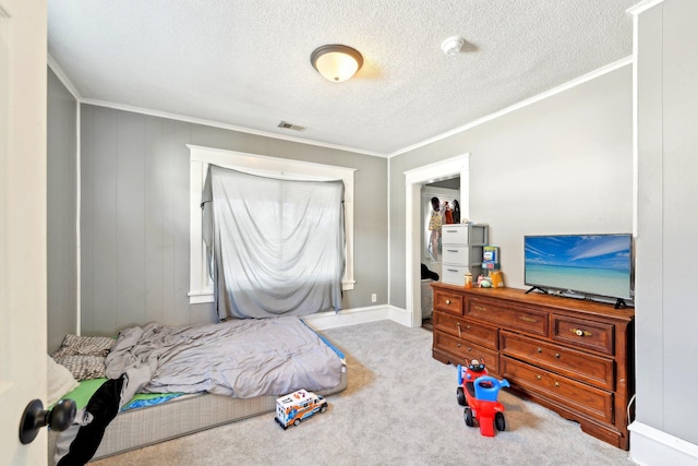 bedroom with a textured ceiling, ornamental molding, carpet, and visible vents