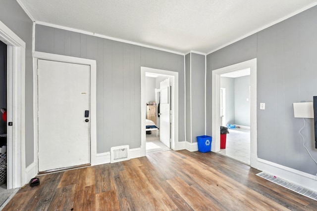 interior space featuring ornamental molding, visible vents, baseboards, and wood finished floors