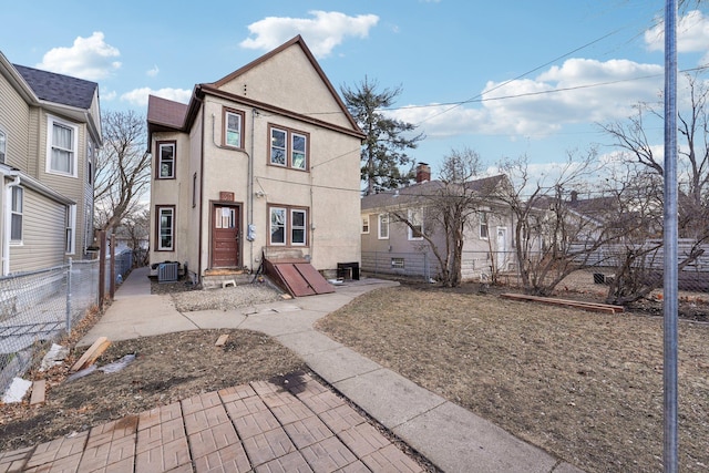 view of front of home featuring central AC unit, a fenced backyard, and stucco siding