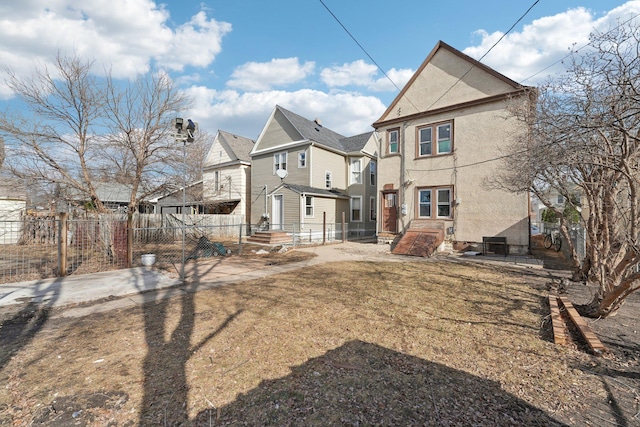 rear view of house featuring fence private yard, a residential view, and stucco siding