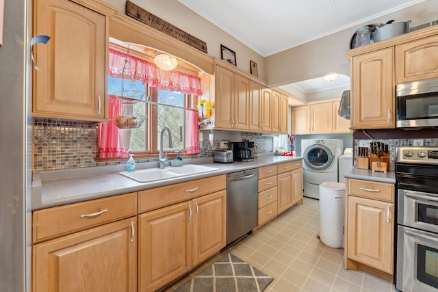 kitchen featuring appliances with stainless steel finishes, light brown cabinets, washing machine and clothes dryer, sink, and backsplash