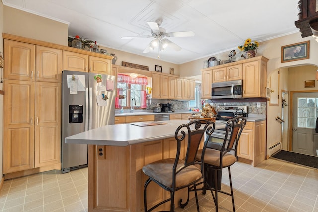 kitchen with baseboard heating, appliances with stainless steel finishes, a center island, tasteful backsplash, and ceiling fan