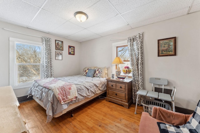 bedroom with a paneled ceiling and light hardwood / wood-style flooring