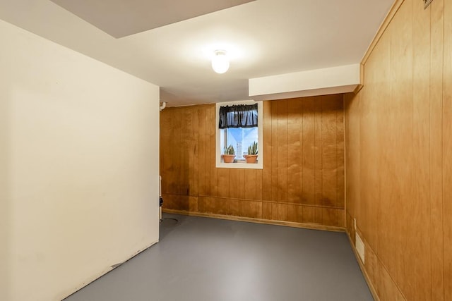 unfurnished room featuring concrete floors and wooden walls