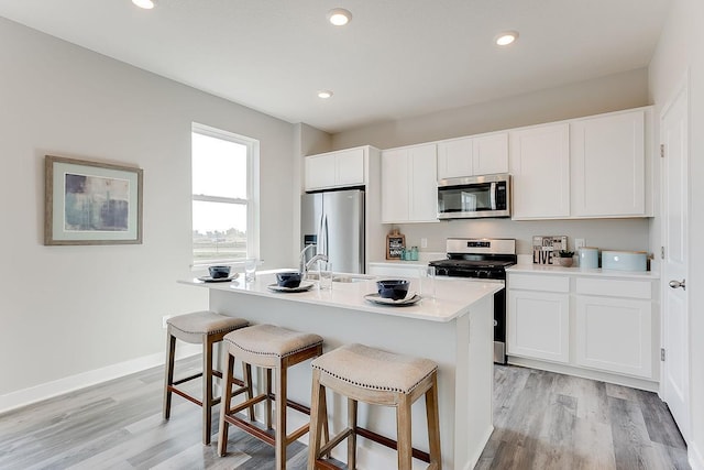 kitchen featuring white cabinetry, an island with sink, light wood-type flooring, and appliances with stainless steel finishes