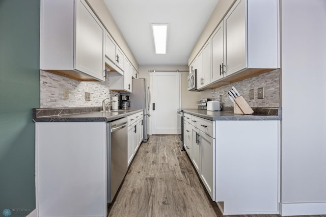 kitchen featuring white cabinets, light hardwood / wood-style floors, stainless steel appliances, and a barn door